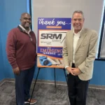 Two speakers standing beside a thank-you sign recognizing SRM ServiceMaster Recovery Management as a summit sponsor at the 2025 Emergency Preparedness Leadership Summit hosted by the Ohio Health Care Association.